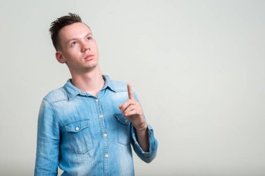 Beyaz arka planda kot gömlek giyen genç adamın stüdyo fotoğrafı.