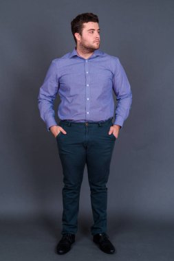 Yakışıklı, şişman, sakallı iş adamının gri arka planda çekilmiş bir fotoğrafı.
