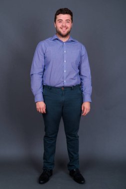 Yakışıklı, şişman, sakallı iş adamının gri arka planda çekilmiş bir fotoğrafı.