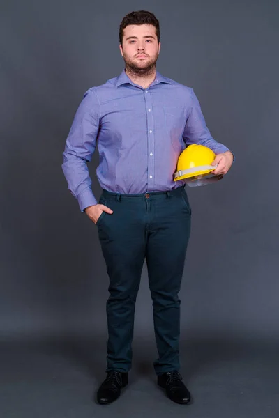 Yakışıklı Şişman Sakallı Adamının Gri Arka Planda Sağlam Şapkalı Mühendis — Stok fotoğraf