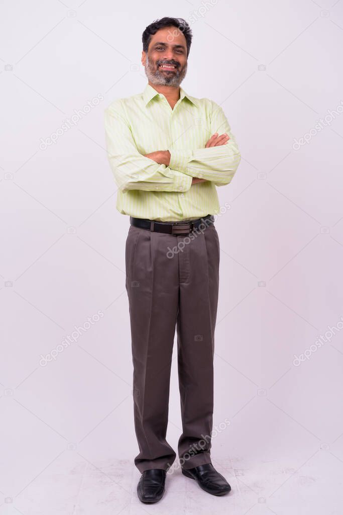 Studio shot of mature handsome bearded Indian businessman against white background