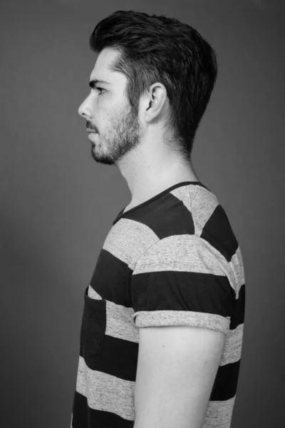 スタジオショットの若いですハンサムなひげを生やした男に対してグレー背景で黒と白 — ストック写真