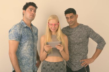 Stüdyo çekim üç çok etnik gruptan oluşan arkadaş birlikte karşı beyaz arka plan dijital tablet kullanma