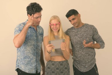 Stüdyo çekim üç çok etnik gruptan oluşan arkadaş birlikte karşı beyaz arka plan dijital tablet kullanma
