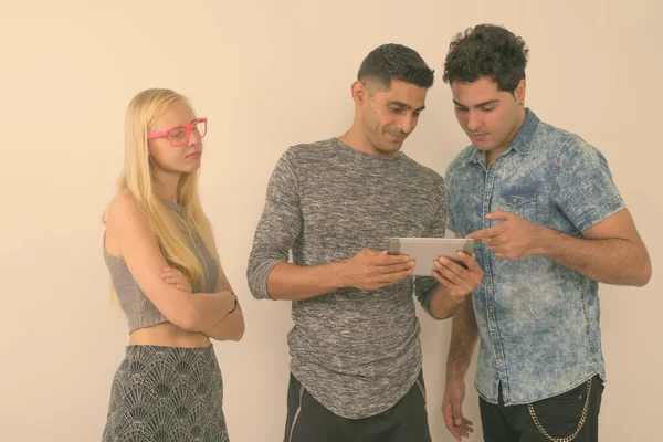 Stüdyo çekim üç çok etnik gruptan oluşan arkadaş birlikte karşı beyaz arka plan dijital tablet kullanma