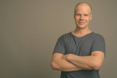 Stüdyo resmi, gri arka planda mavi gömlekli kel bir adam.