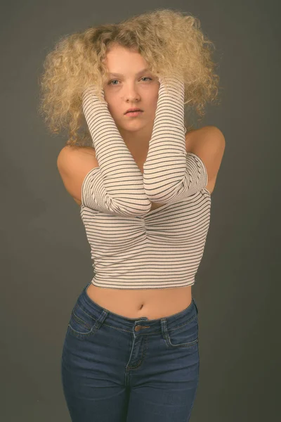 Sarı Kıvırcık Saçlı Gri Arka Planda Genç Güzel Bir Kadının — Stok fotoğraf