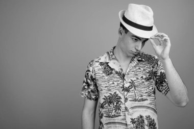 Hawaii gömleği ve şapkası giyen yakışıklı turistin siyah beyaz tatil için hazır olduğu bir stüdyo fotoğrafı.