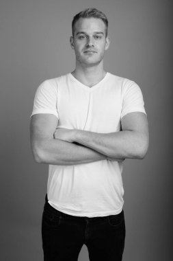 Stüdyo resmi, sarı saçlı, siyah beyaz arka planda genç ve yakışıklı bir adam.