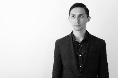 Takım elbiseli genç ve yakışıklı işadamının siyah beyaz arka planda çekilmiş bir fotoğrafı.