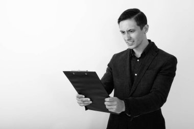 Takım elbiseli genç ve yakışıklı işadamının siyah beyaz arka planda çekilmiş bir fotoğrafı.