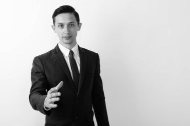 Takım elbiseli genç ve yakışıklı işadamının siyah beyaz arka planda çekilmiş bir fotoğrafı.