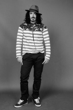 Kıvırcık saçlı, bıyıklı, siyah beyaz arka planlı yakışıklı adamın stüdyo fotoğrafı.