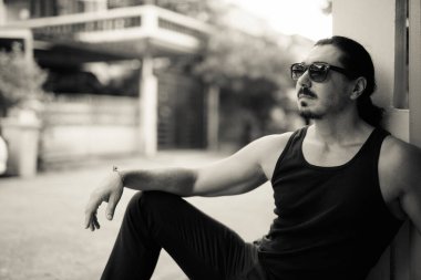 Sokaklarda siyah beyaz, kıvırcık saçlı ve bıyıklı yakışıklı bir adamın portresi.