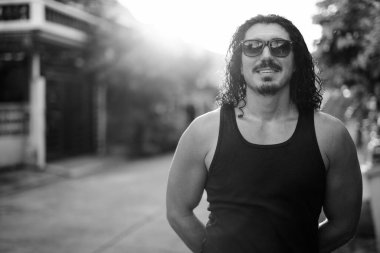 Sokaklarda siyah beyaz, kıvırcık saçlı ve bıyıklı yakışıklı bir adamın portresi.