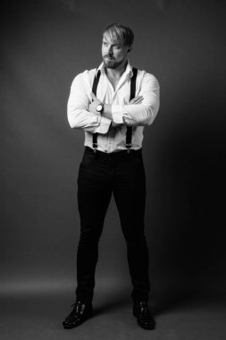 Stüdyo resmi, sarı saçlı sakallı adam siyah beyaz arka planda.