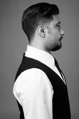 Genç sakallı İranlı işadamının atölye çekimi siyah beyaz arka planda gri