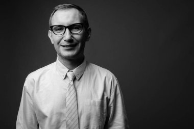 İş adamının gri arka planda siyah beyaz gözlük taktığı bir fotoğraf.