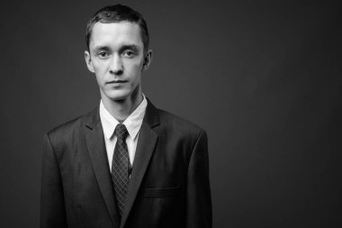 Siyah beyaz gri arka planda takım elbise giyen genç işadamının stüdyo fotoğrafı.