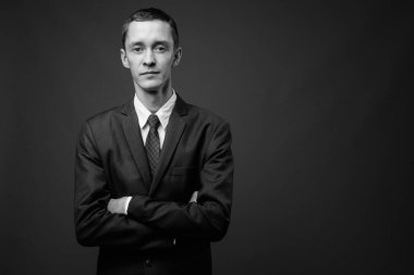 Siyah beyaz gri arka planda takım elbise giyen genç işadamının stüdyo fotoğrafı.