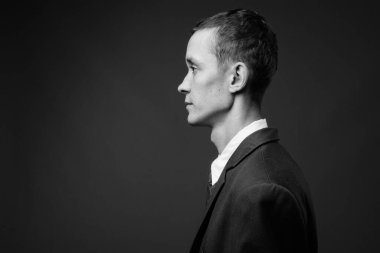 Siyah beyaz gri arka planda takım elbise giyen genç işadamının stüdyo fotoğrafı.