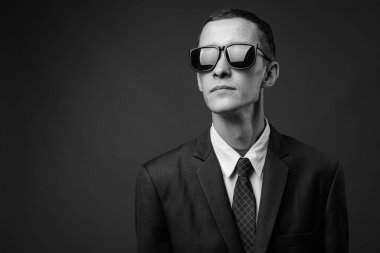 Siyah beyaz gri arka planda takım elbise giyen genç işadamının stüdyo fotoğrafı.