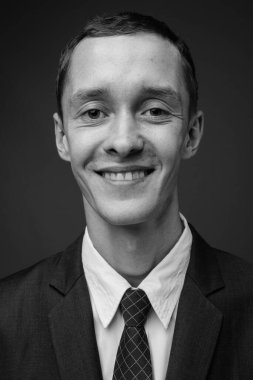 Siyah beyaz gri arka planda takım elbise giyen genç işadamının stüdyo fotoğrafı.