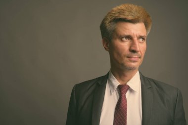 Stüdyo çekiminde sarı saçlı iş adamı gri arka planda.