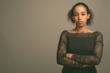 Gri arka planda genç ve güzel Afrikalı bir kadının stüdyo çekimi.
