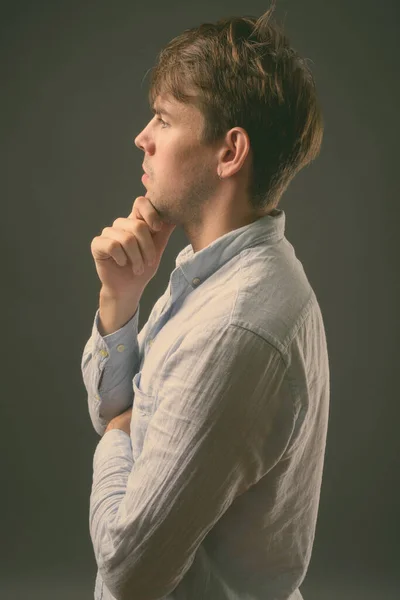 演播室拍摄年轻英俊男子穿着灰色背景的蓝色衬衫 — 图库照片