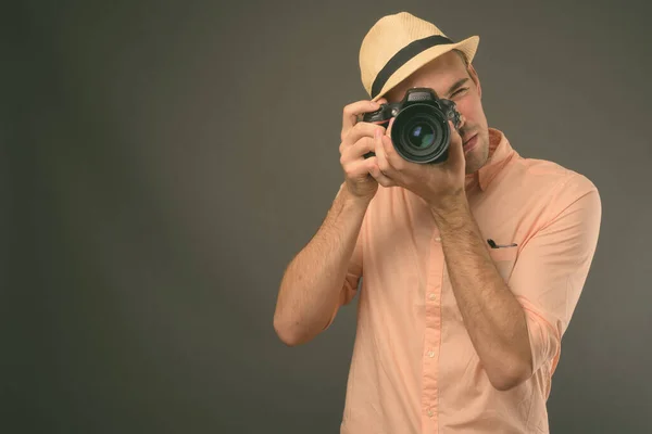 スタジオショットの若いですハンサムな観光客の男の帽子を身に着けている灰色の背景 — ストック写真