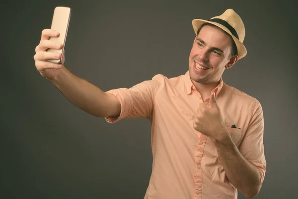 Studioaufnahme Eines Jungen Gutaussehenden Touristenmannes Mit Hut Vor Grauem Hintergrund — Stockfoto