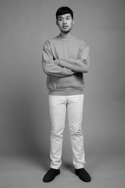 スタジオショットの若いですアジアの男身に着けているセーターに対してグレー背景で黒と白 — ストック写真