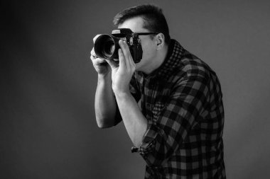 Siyah-beyaz gri arka planda şık giyinen yakışıklı bir adamın stüdyo fotoğrafı.