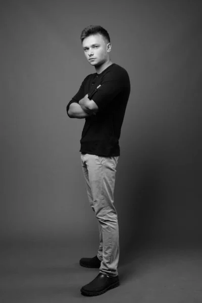 stock image Studio shot of young handsome man wearing black shirt against gray background in black and white