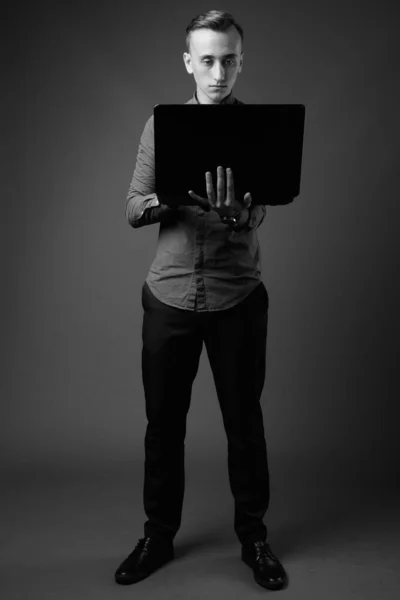 Студийный Снимок Молодого Привлекательного Бизнесмена Использующего Ноутбук Сером Фоне Черно — стоковое фото