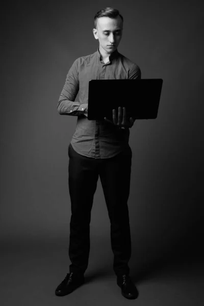 Студийный Снимок Молодого Привлекательного Бизнесмена Использующего Ноутбук Сером Фоне Черно — стоковое фото