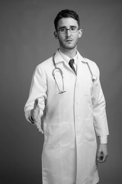 Estudio Joven Guapo Doctor Con Anteojos Sobre Fondo Gris Blanco — Foto de Stock