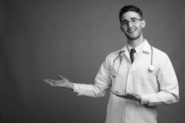 Estudio Joven Guapo Doctor Con Anteojos Sobre Fondo Gris Blanco — Foto de Stock