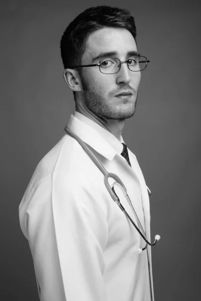 Estudio Joven Guapo Doctor Con Anteojos Sobre Fondo Gris Blanco — Foto de Stock