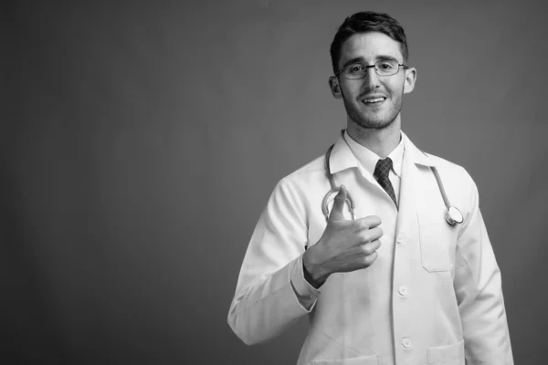 Studio Záběr Mladý Pohledný Muž Lékař Nosí Brýle Proti Šedé — Stock fotografie