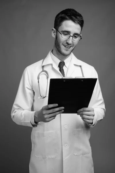 Studio Shot Young Handsome Man Doctor Eyeglasses Holding Clipboard Gray — Stock Photo, Image