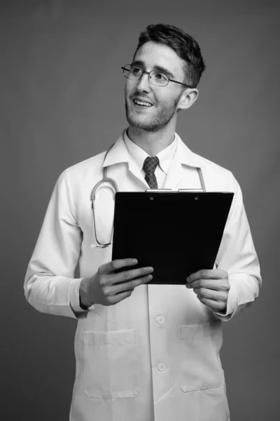 Studio Shot Young Handsome Man Doctor Eyeglasses Holding Clipboard Gray — Stock Photo, Image