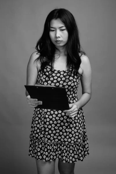 Studio Shot Mujer Asiática Usando Vestido Mientras Sostiene Portapapeles Contra — Foto de Stock