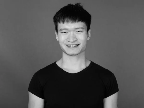 スタジオショットの若いです中国人男性身に着けている黒シャツに対してグレー背景で黒と白 — ストック写真