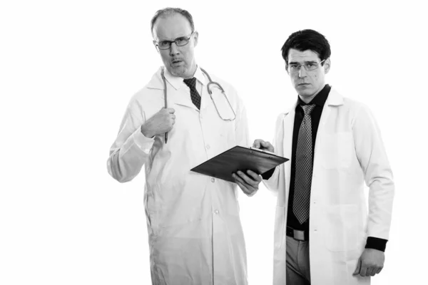 成人男医生与年轻男医生在黑白背景下隔离的演播室拍摄 — 图库照片