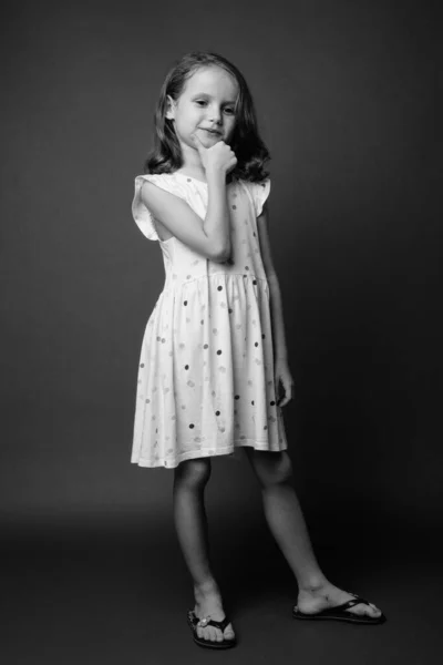 电影制片厂拍摄的一个年轻可爱的金发姑娘穿着灰色背景的白衣 — 图库照片