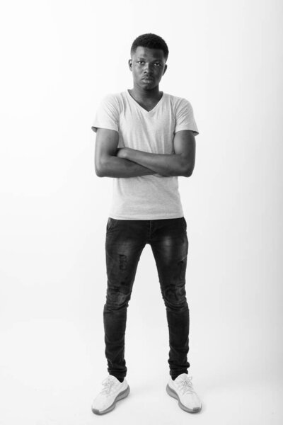 Studio shot of young African man against white background in black and white