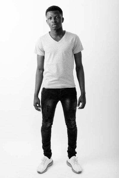 Studio shot of young African man against white background in black and white