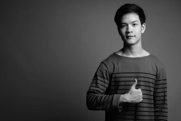 Studio Záběr Mladého Pohledného Asijského Muže Proti Šedé Pozadí Černé — Stock fotografie